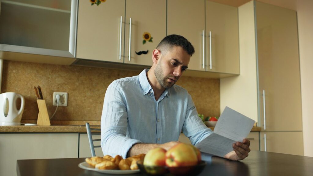 Homeowner reviews roof financing paperwork beside a calculator and house keys at a kitchen table.