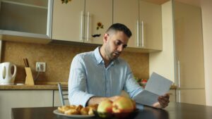 Homeowner reviews roof financing paperwork beside a calculator and house keys at a kitchen table.